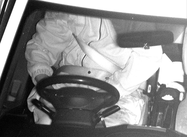 Photo of a driver in a car showing incorrect use of seatbelt