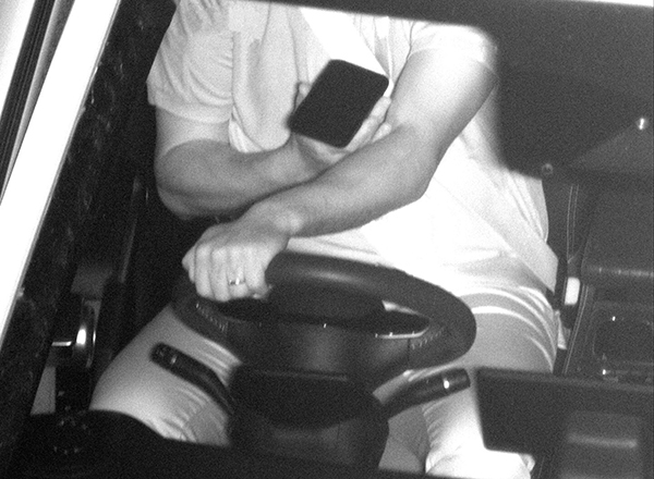 photo of a driver in a car with a phone in his hand while driving