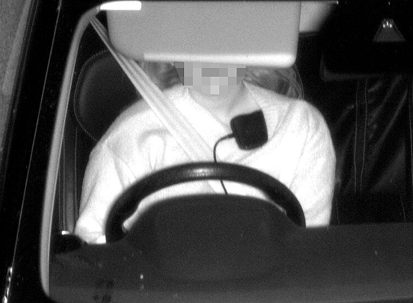 photo of a driver in a car with a phone on his body while driving