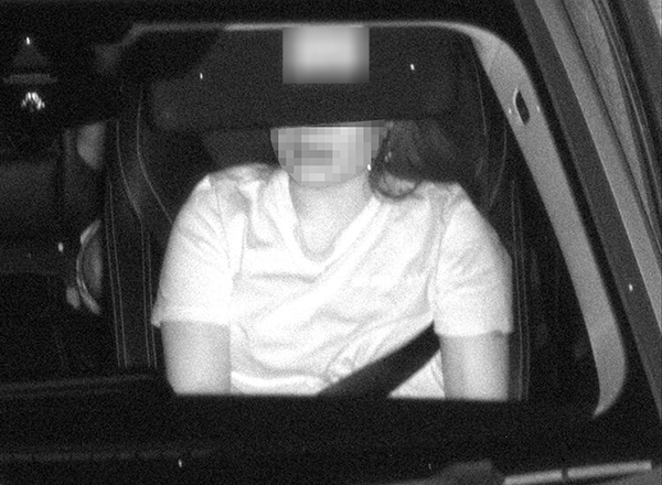 Photo of a passenger in a car showing incorrect use of seatbelt